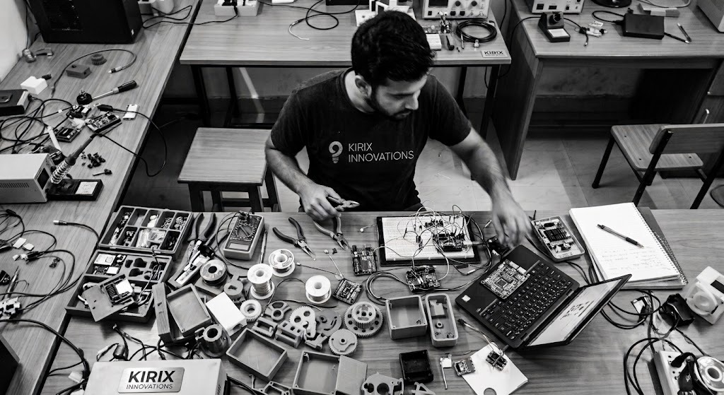 A Kirix engineer assembling electronics at a workbench covered in components and prototypes